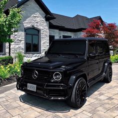 a black mercedes g - class parked in front of a house