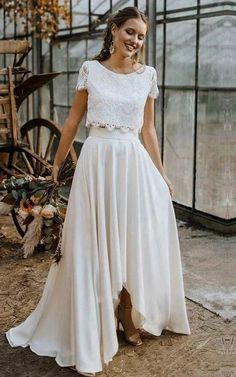 a woman standing in front of a greenhouse wearing a white dress