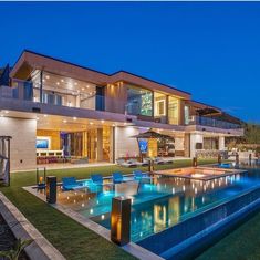 a large house with a swimming pool in the front yard at night, lit up by lights