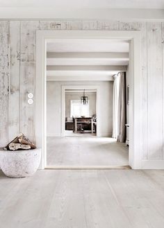 an open door leading to a living room with white walls and parquet flooring