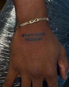 a person's hand with a tattoo saying by any means necessary