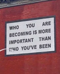 a sign on the side of a building that says, who you are becoming is more important than who you've been