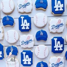 cookies decorated with royal blue and white icing are arranged in the shape of los angeles dodgers baseball caps