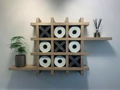 a wooden shelf with several rolls of toilet paper and a potted plant on it