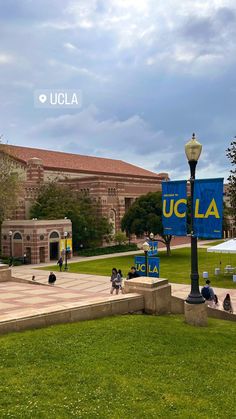 people are sitting on the grass in front of an old building with a sign that reads ucla