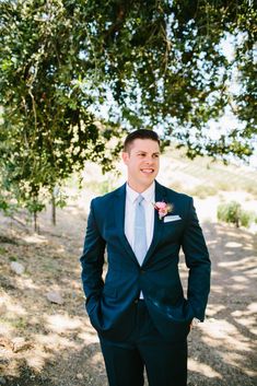 a man in a suit standing under a tree