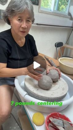 an older woman sitting in front of a pottery wheel and making something out of clay