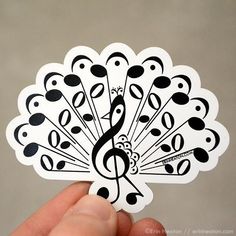 a hand holding a black and white sticker with musical notes on it's side