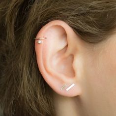 a close up of a person's ear with two small piercings on it