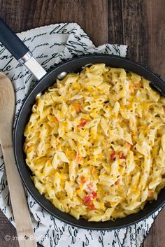 a skillet filled with macaroni and cheese on top of a wooden table