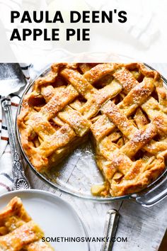 an apple pie with one slice cut out and two plates on the table next to it