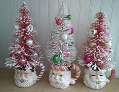 three ceramic christmas trees with santa claus and other ornaments on them, all decorated in pink and white