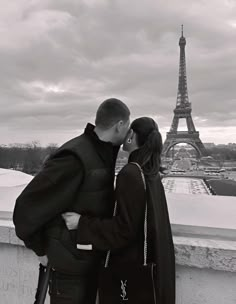 a man and woman standing next to each other in front of the eiffel tower