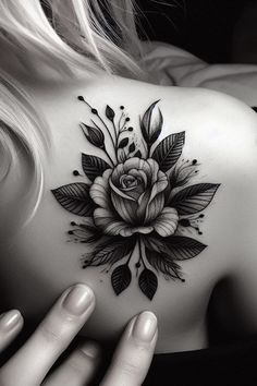 a woman's back with a rose tattoo on her left shoulder and the other hand