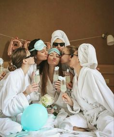 three women in robes kissing and drinking champagne