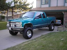 a blue pick up truck parked in front of a house