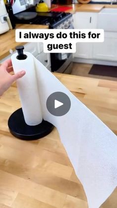 a person holding a roll of paper on top of a wooden table next to a kitchen counter