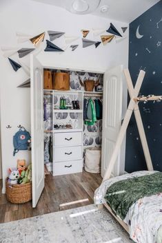 a bedroom with an open closet and clothes hanging on the wall, next to a child's bed