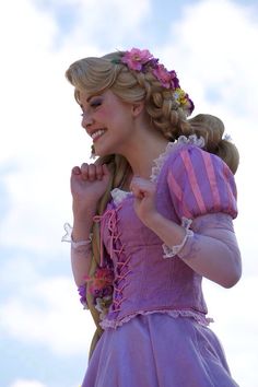 a woman in a purple dress with braids and flowers on her head is posing for the camera