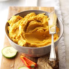 a bowl filled with hummus next to sliced cucumbers