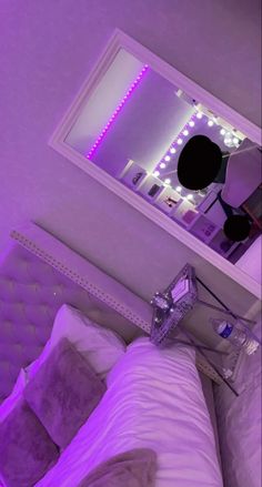 there is a bed with purple lights on the headboard and pillows in front of it