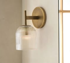 a wall light that is on the side of a wall with a glass shade over it