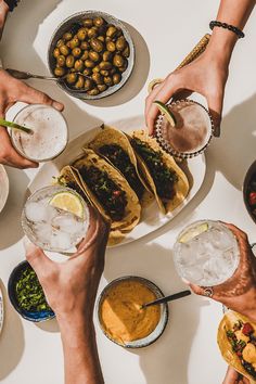 several people are eating and drinking at a table with plates of food, drinks and condiments