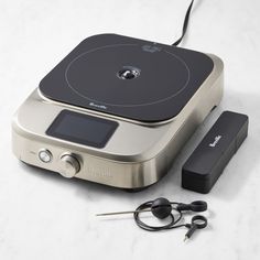 an electronic device with ear buds and headphones on a white counter top next to a charger