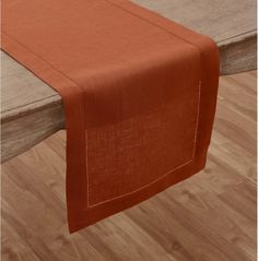 an orange linen table runner on top of a wooden dining room table with wood flooring