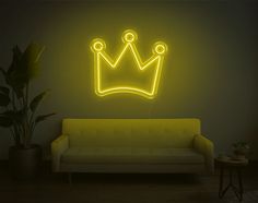 a living room with a couch and a neon crown on the wall next to it