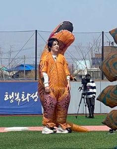 a man in an orange costume standing on top of a baseball field