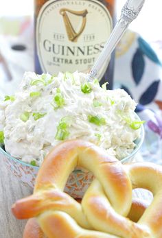 two pretzels and a bowl of food on a table next to a beer