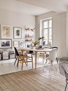 a dining room table with white chairs and a christmas tree in the corner next to it