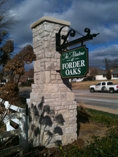 a sign that is on the side of a brick pillar in front of a road