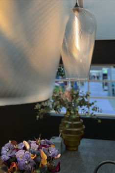 a vase filled with purple flowers sitting on top of a table next to a lamp