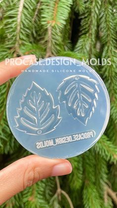 a person holding up a clear plastic object in front of a pine tree with the words procreed design molds on it