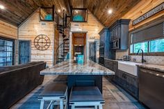 a kitchen and living room inside of a log cabin with wood walls, flooring and ceiling