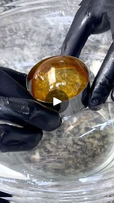 a person in black gloves is holding a bowl with something yellow and brown on it