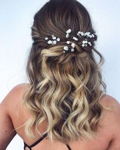 the back of a woman's head with long wavy hair and flowers in her hair