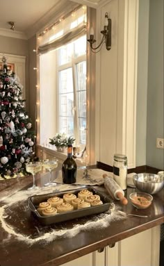 a christmas tree is in the corner of a kitchen with cookies and other foods on the counter