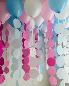 balloons and streamers hanging from the ceiling in pink, blue, and white colors