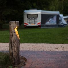 a wooden post with a light on it in front of a campervane