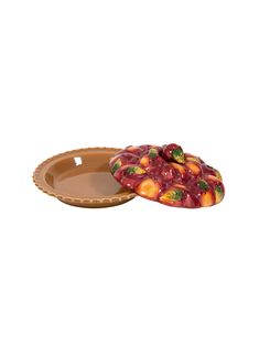 an orange and red fruit dish sitting on top of a white surface next to a brown plate