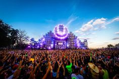 a large group of people standing in front of a stage with bright lights on it