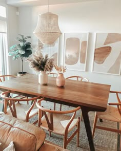 a dining room table with chairs and pictures on the wall