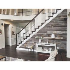 a living room filled with furniture and a stair case in front of a wooden wall