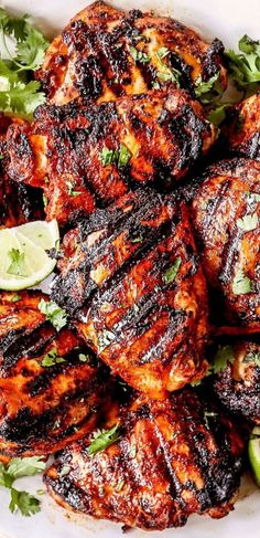 grilled chicken with garnishes and limes on a white platter