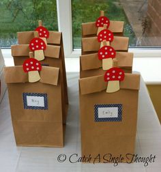 some brown paper bags with red bows and tags on them sitting on a table near a window