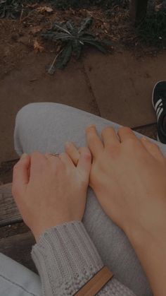 a person sitting on a bench with their hand resting on the leg of someone's foot