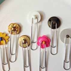 there are several pins and clips on the white plate, one has a pink flower